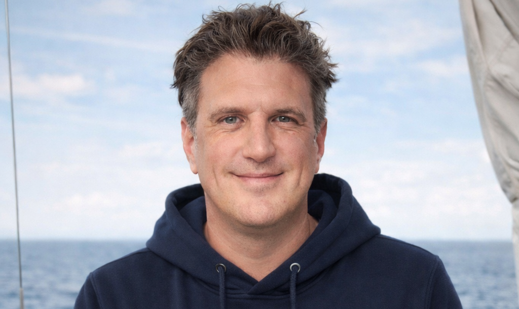 Jan auf Segelyacht am Ruder. im Hintergrund ist Meer.