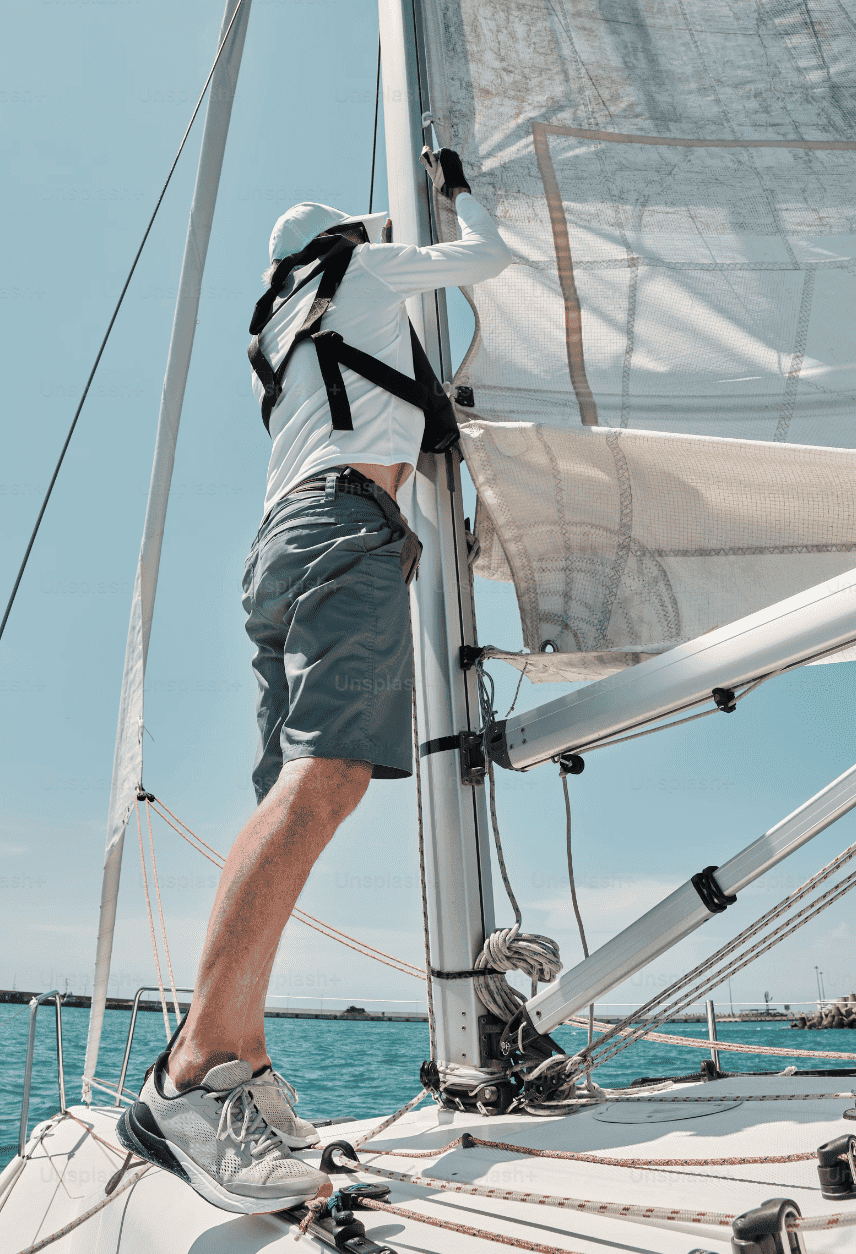 Skipper auf Segelyacht am Mast Segel bergen