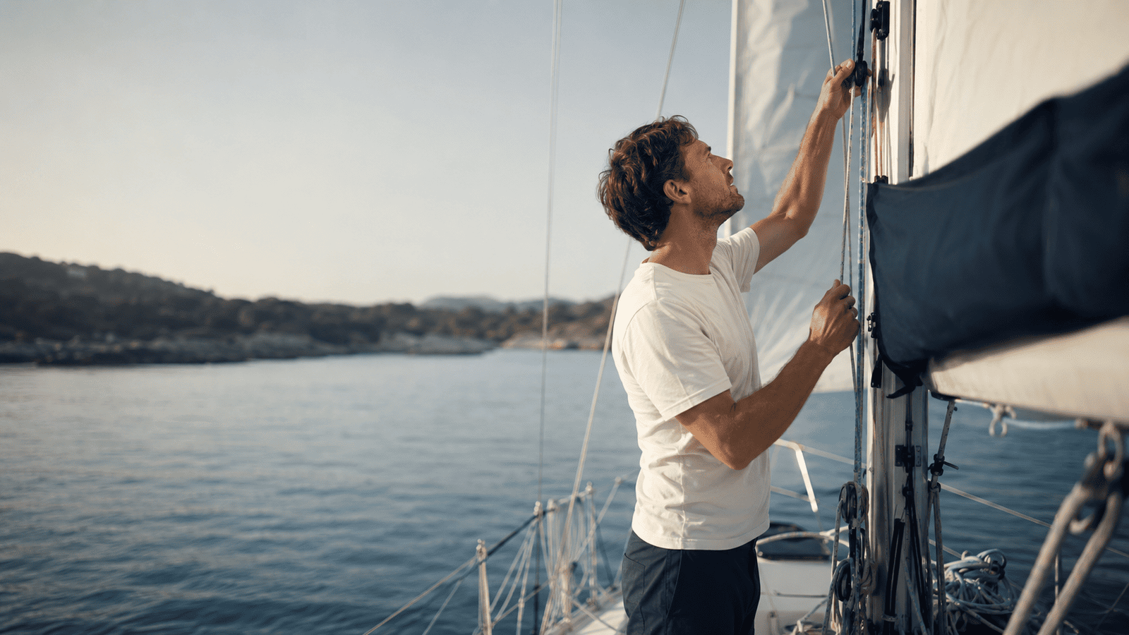 Mann steht beim Segeln lernen am Mast auf einer Segel Yacht